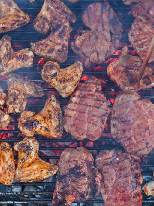 Grillfleisch liegt auf einem Holzkohlegrill.