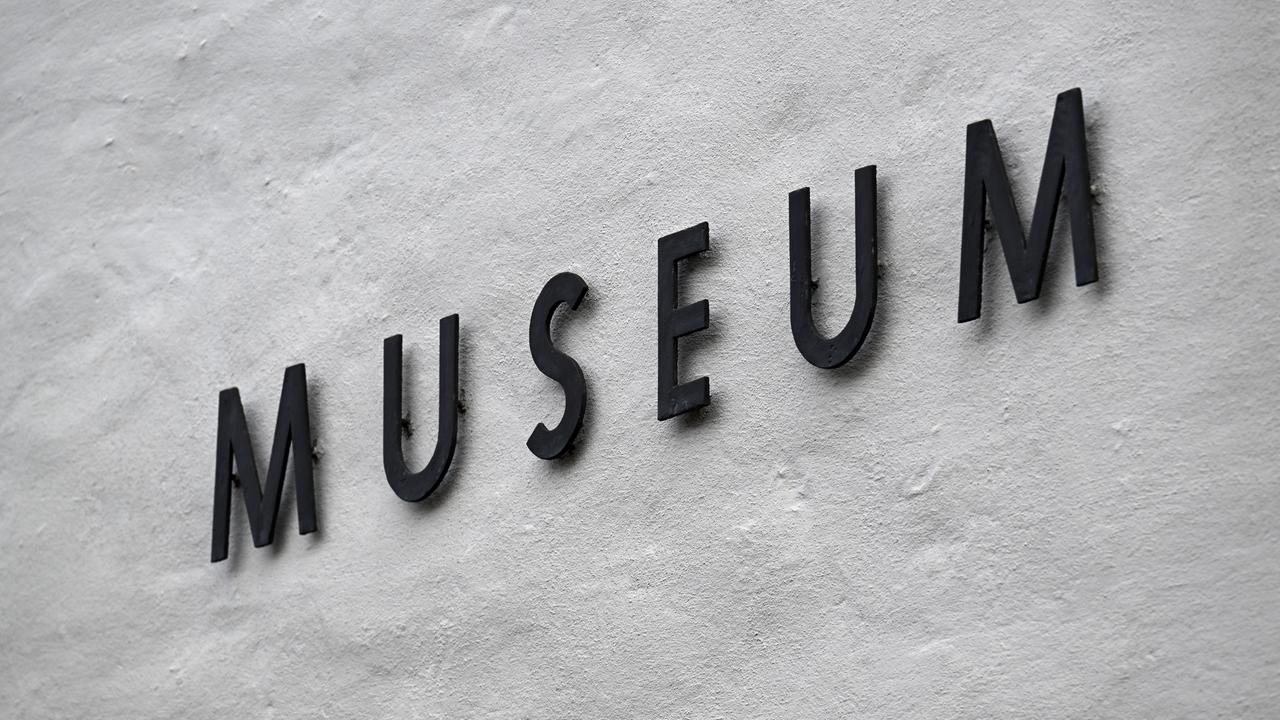 Das Bild zeigt einen schwarzen "Museum"-Schriftzug an einer Hauswand. 