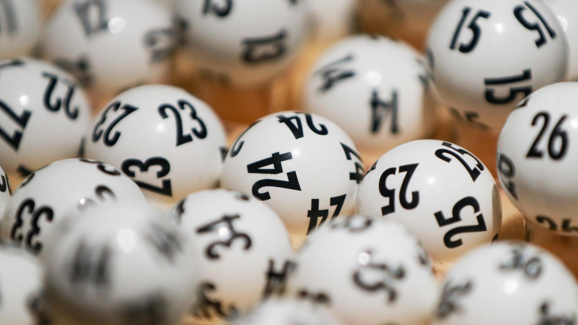 Weiße Lottokugeln mit schwarzen Zahlen liegen übereinander.