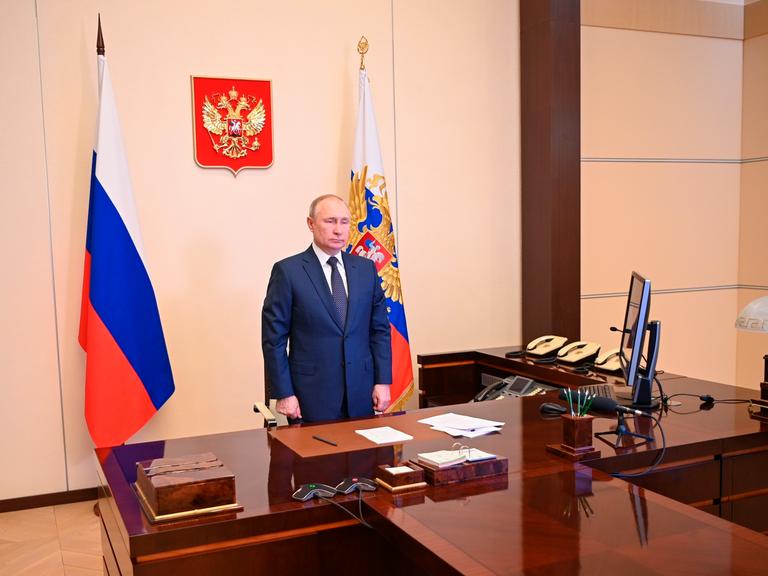 Der russische Präsident Wladimir Putin im Kreml am Schreibtisch. Hinter ihm steht eine russische Fahne.