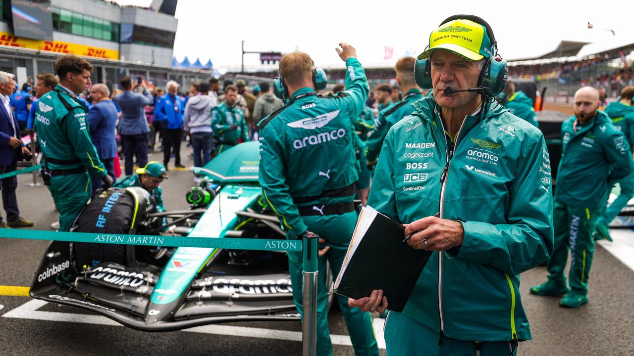 Adrian Newey geht in grünem Outfit vor einem Rennauto in der Startaufstellung entlang.