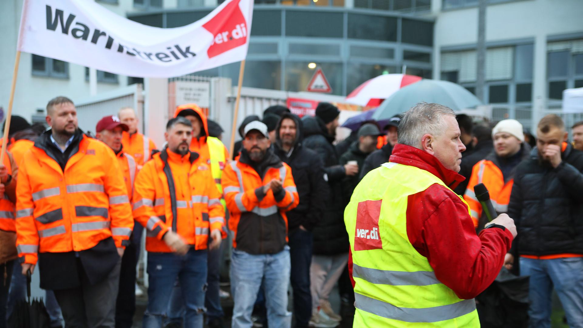 Streikende stehen mit einem Banner mit der Aufschrift "Warnstreik" vor dem Werkstor der Kölner Abfallwirtschaftsbetriebe. Streikende stehen mit einem Banner mit der Aufschrift "Warnstreik" vor dem Werkstor der Kölner Abfallwirtschaftsbetriebe.