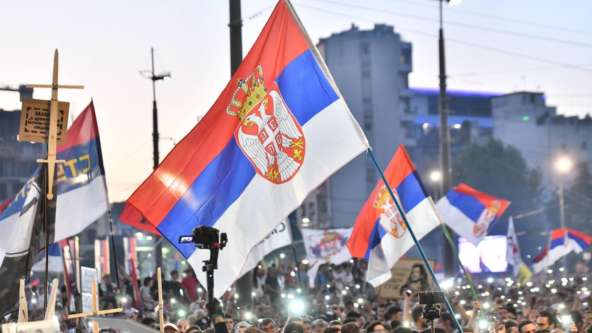 Tausende Menschen demonstrieren in Belgrad gegen die Regierung, sie schwenken serbische Flaggen und leuchten mit ihren Handy-Taschenlampen