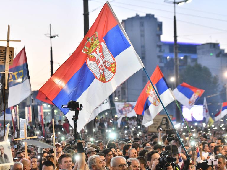 Tausende Menschen demonstrieren in Belgrad gegen die Regierung, sie schwenken serbische Flaggen und leuchten mit ihren Handy-Taschenlampen