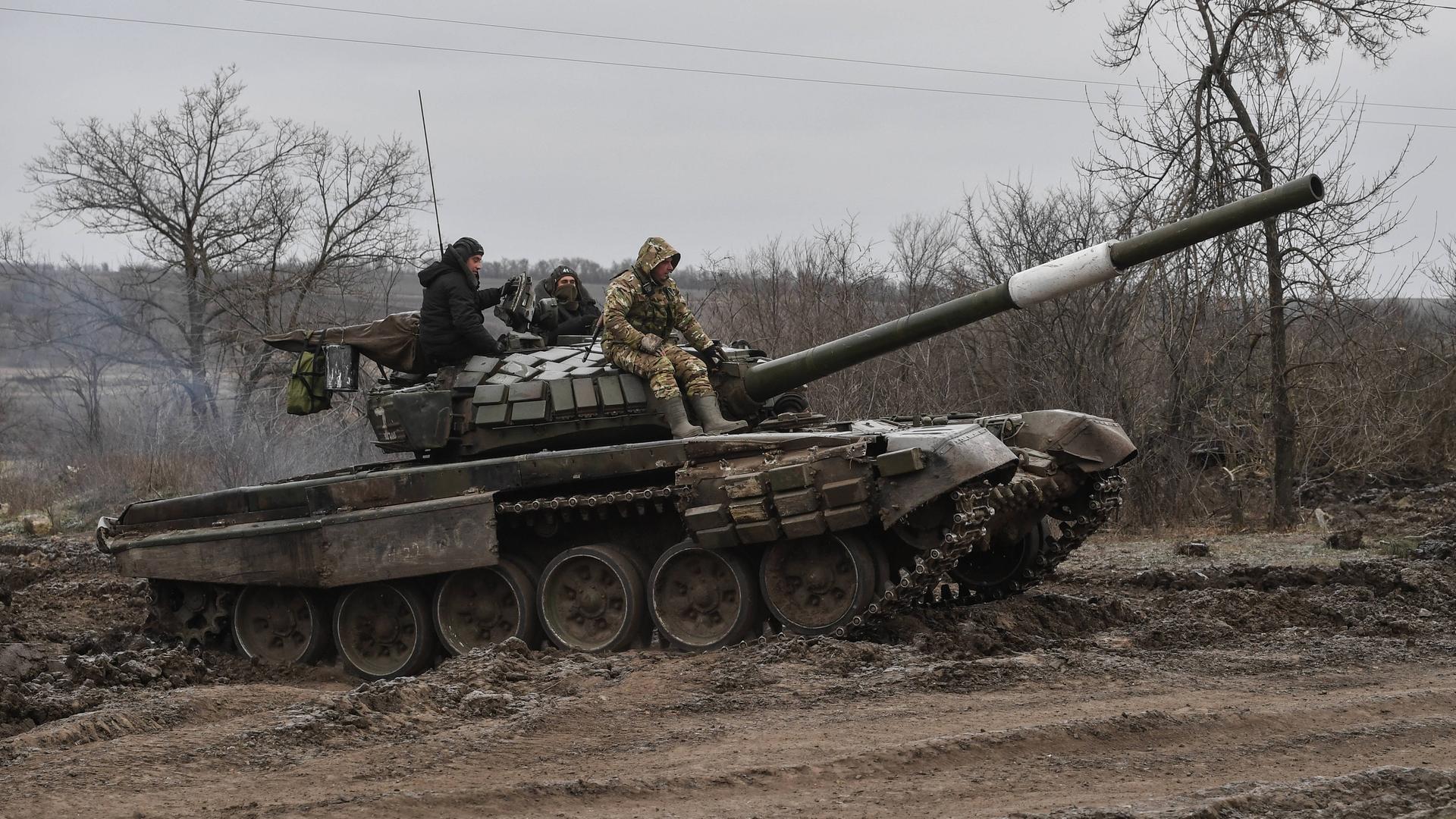 Ein Panzer auf dem russische Soldaten fahren.