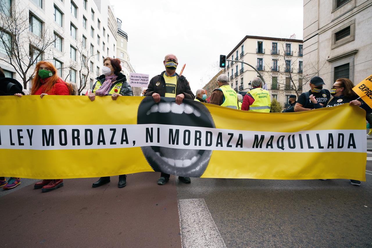 Protestierende laufen mit einem Banner gegen das sogenannte "Maulkorbgesetz" durch die Straßen von Madrid.