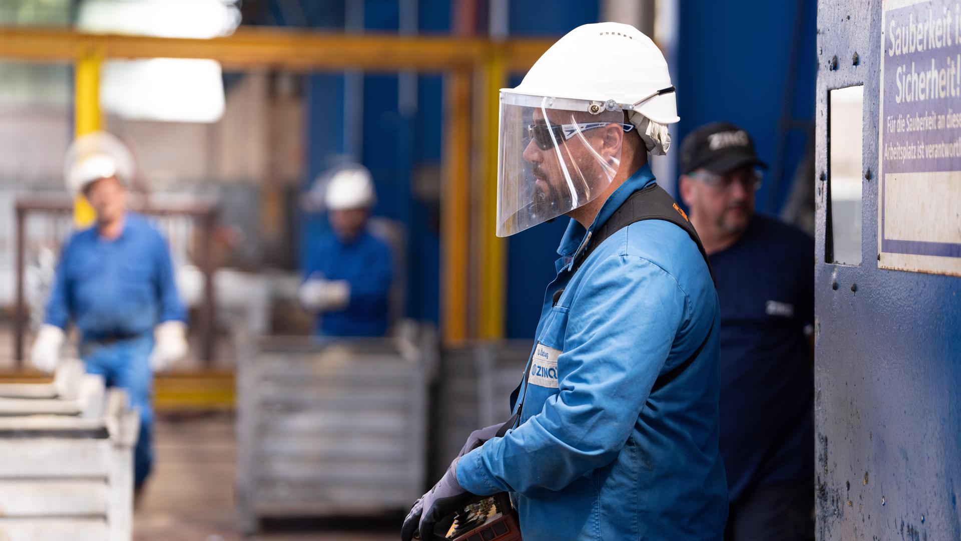 Ein Arbeiter mit Schutzhelm und Visier bei ihrer Arbeit.