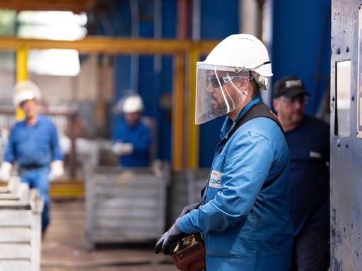 Ein Arbeiter mit Schutzhelm und Visier bei ihrer Arbeit.