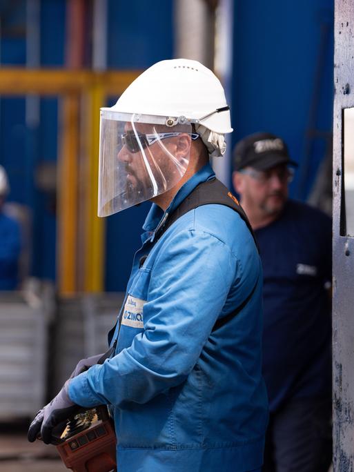 Ein Arbeiter mit Schutzhelm und Visier bei ihrer Arbeit.