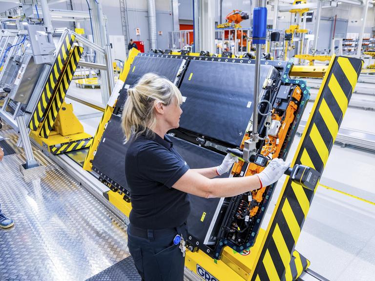 Eine Frau steht in einer Fertigungshalle und stellt Antriebsbatterien für ein vollelektrisches Mercedes-Benz-Modell her.