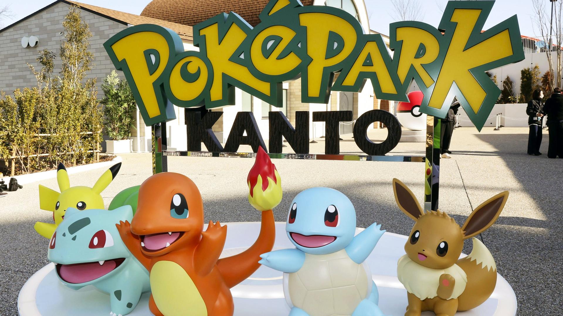 Mehrere Pokémon-Figuren vor einem Schild mit der Aufschrift Poképark Kanto. 