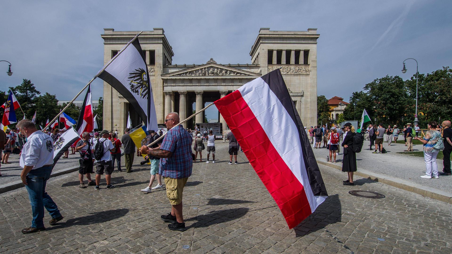 Reichsbürger am Königsplatz in München. Einer trägt die Preußenflagge, ein anderer die Flagge des deutschen Kaiserreichs