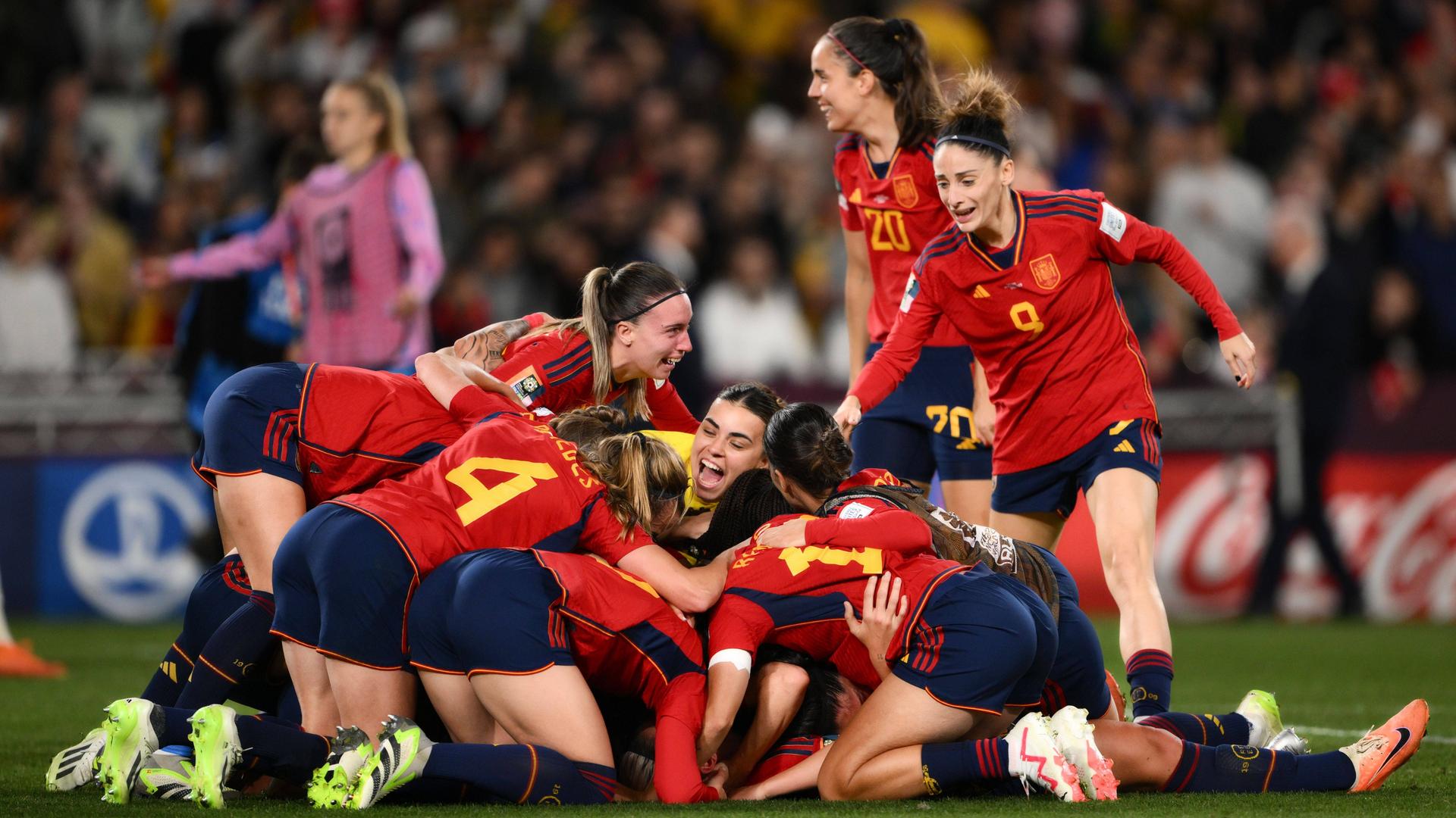 Spaniens Fußballerinnen jubeln über ihren ersten Titel bei einer Fußball-WM. Die Spielerinnen umarmen sich als Gruppe, einige liegen auf dem Boden. Spaniens Fußballerinnen jubeln über ihren ersten Titel bei einer Fußball-WM. Die Spielerinnen umarmen sich als Gruppe, einige liegen auf dem Boden.