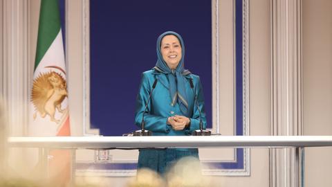 Die Parteivorsitzende der Volksmudschahedin Maryam Rajavi bei einer Rede. Sie trägt ein türkisenes Kostüm und ein türkisfarbenes Kopftuch.