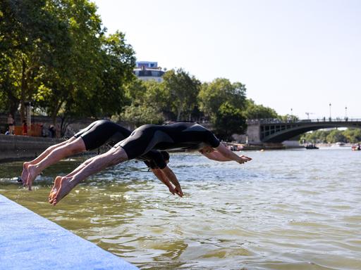 Zwei Menschen springen mit einem Kopfsprung in den Fluss Seine in Paris.