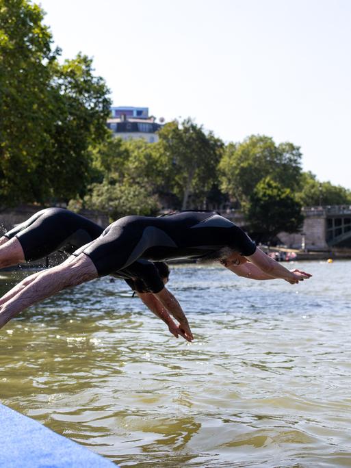 Zwei Menschen springen mit einem Kopfsprung in den Fluss Seine in Paris.