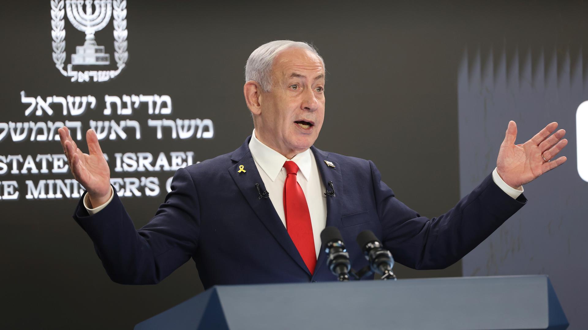Der israelische Premier Benjamin Netanjahu bei einer Pressekonferenz in Jerusalem. Im Hintergrund sind hebräische Schriftzeichen zu erkennen, er scheint zu gestikulieren. 
