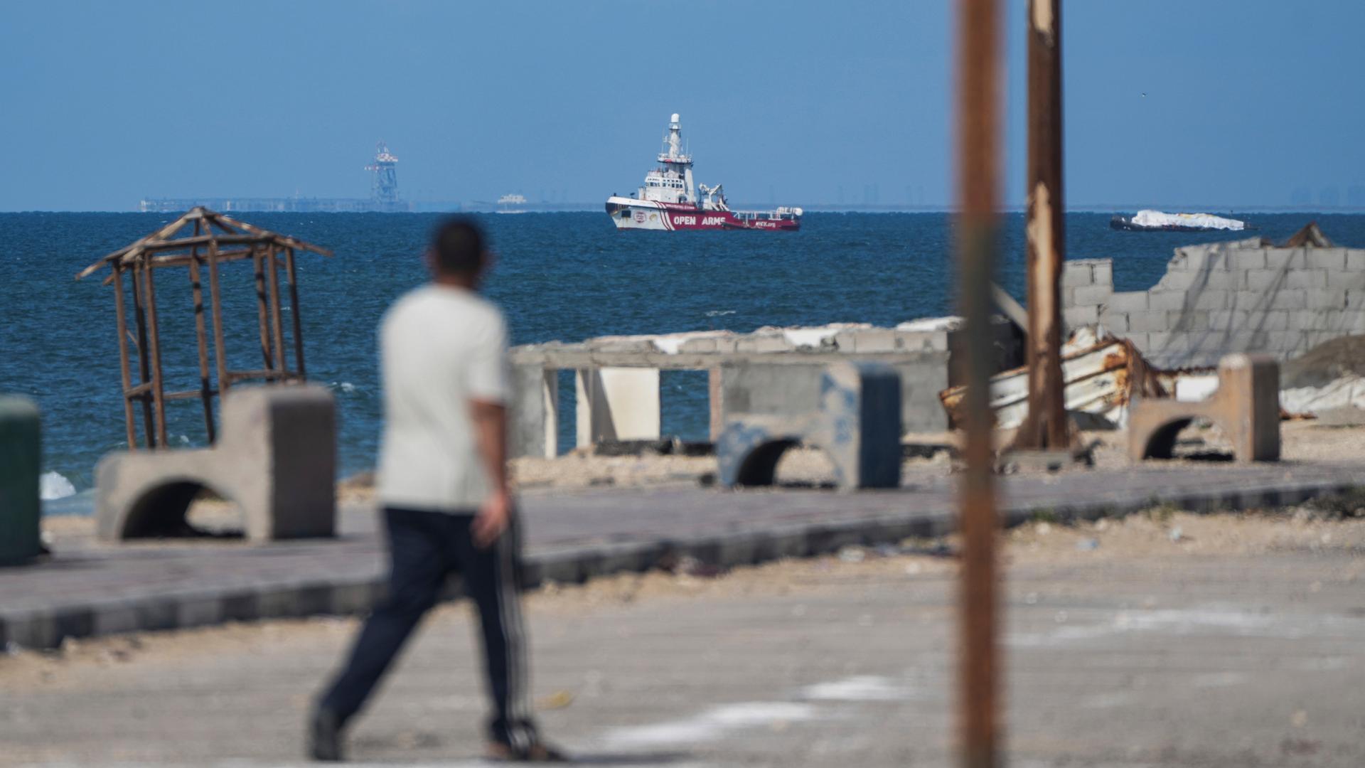 Das Schiff der Hilfsorganisation "Open Arms" nähert sich der Küste des Gazastreifens. Das Foto wurde von Land aus aufgenommen. Im Vordergund ist unscharf ein Mensch abgebildet.