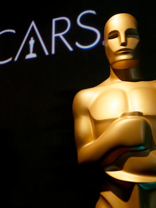 Eine Oscar-Statue und der Schriftzug "Oscars" ist vor einem schwarzen Hintergrund zu sehen. 