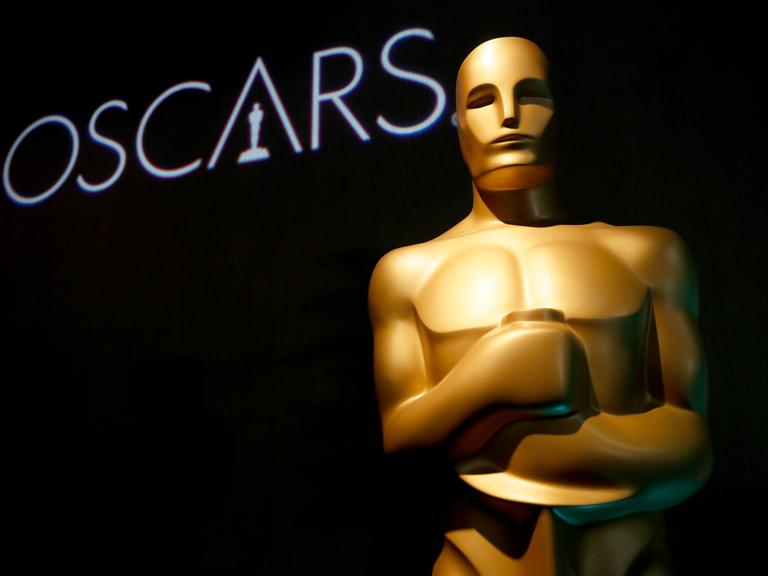 Eine Oscar-Statue und der Schriftzug "Oscars" ist vor einem schwarzen Hintergrund zu sehen. 