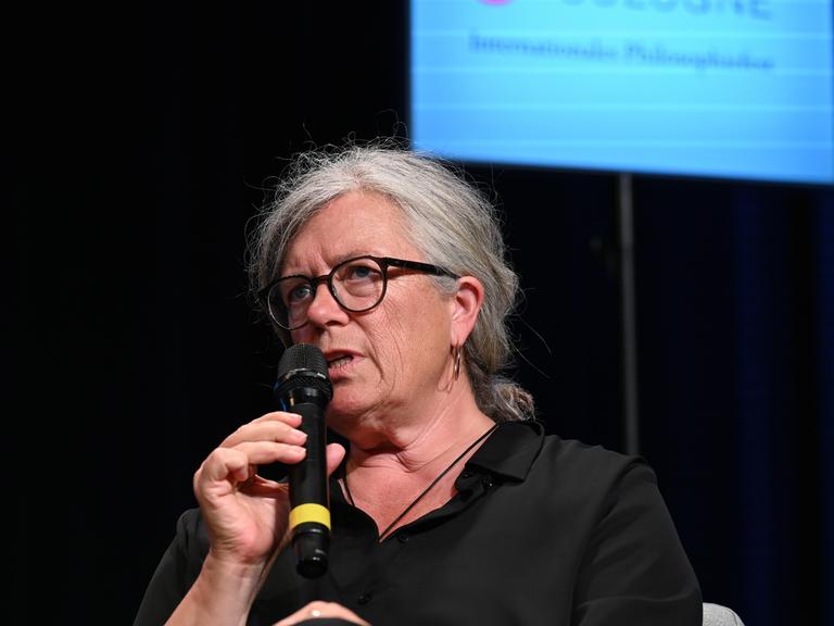 Rechtsanwältin Christina Clemm, Rechtsanwältin für Straf-und Familienrecht in Berlin. sitzt auf einer Bühne und spricht in ein Mikrofon. Rechtsanwältin Christina Clemm, Rechtsanwältin für Straf-und Familienrecht in Berlin. sitzt auf einer Bühne und spricht in ein Mikrofon.