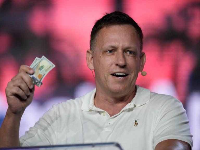 Peter Thiel, Mitbegründer von PayPal and Palantir, zeigt Mitgliedern ein paar 100-Dollar-Noten während einer Bitcoin Konferenz am 7. April 2022 in Miami Beach, Florida. Er gilt als Sponsor der Republikaner und von JD Vance.