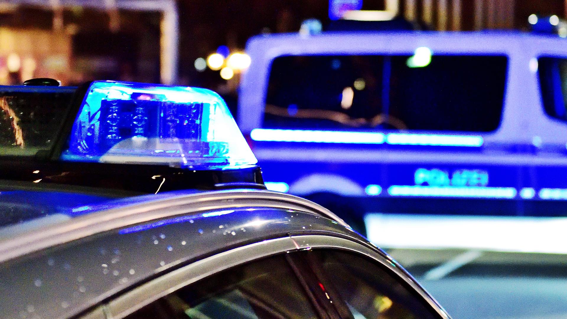 Zwei Polizeiwagen mit Blaulicht stehen nachts auf der Straße.