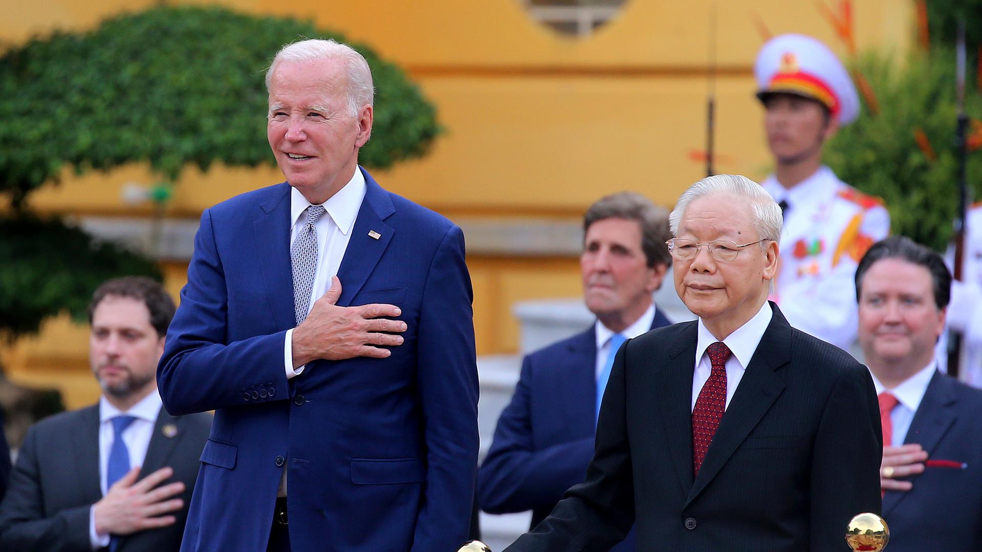 US-Präsident Biden (li.) und der Generalsekretär der Kommunistischen Partei Vietnams, Nguyen Phu Trong, stehen nebeneinander. Biden hält die rechte Hand auf das Herz.