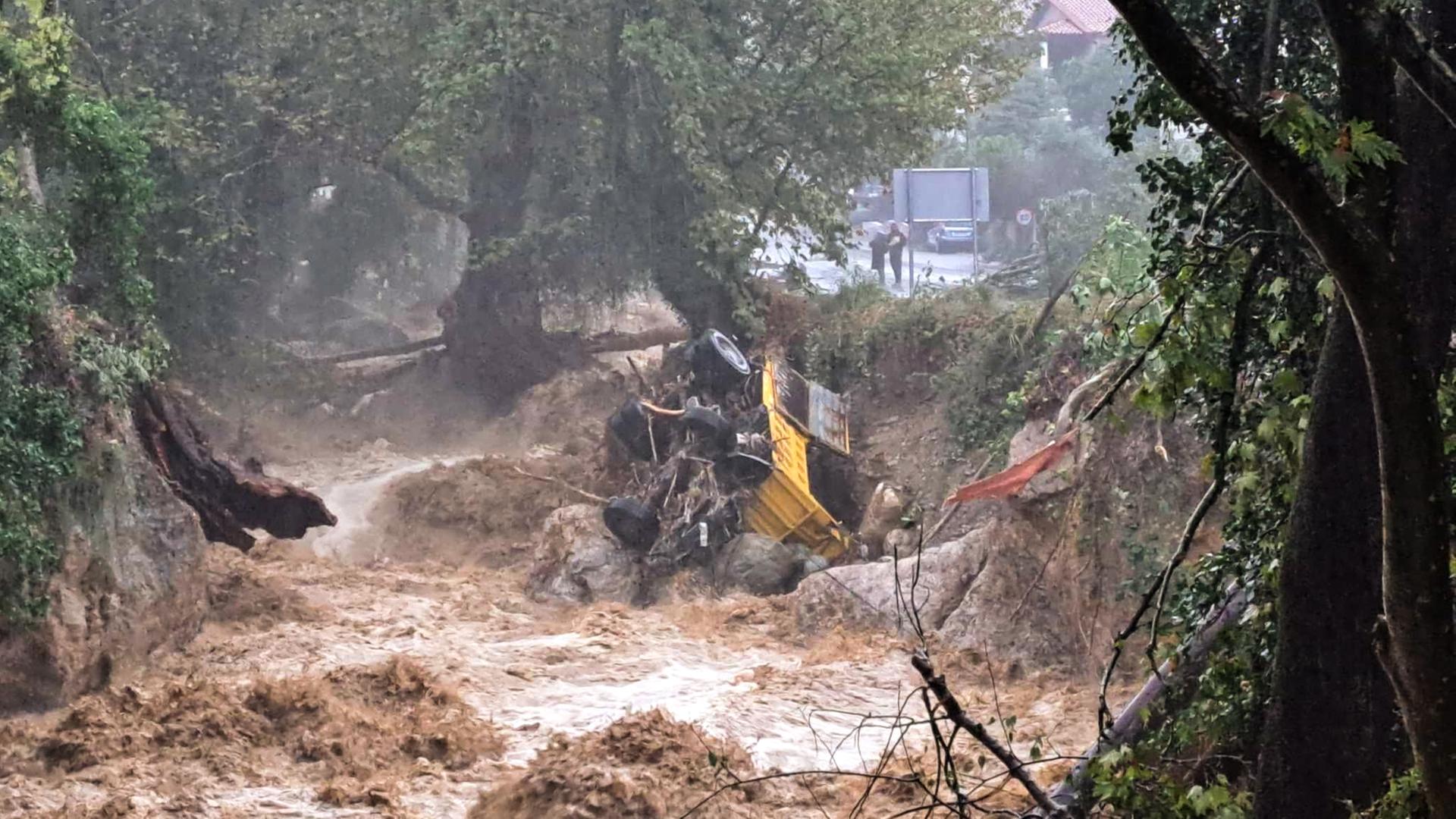 Das Buld zeigt einen reißenden Fluss in der Innenstadt von Volos, in den ein Auto gestürzt ist.