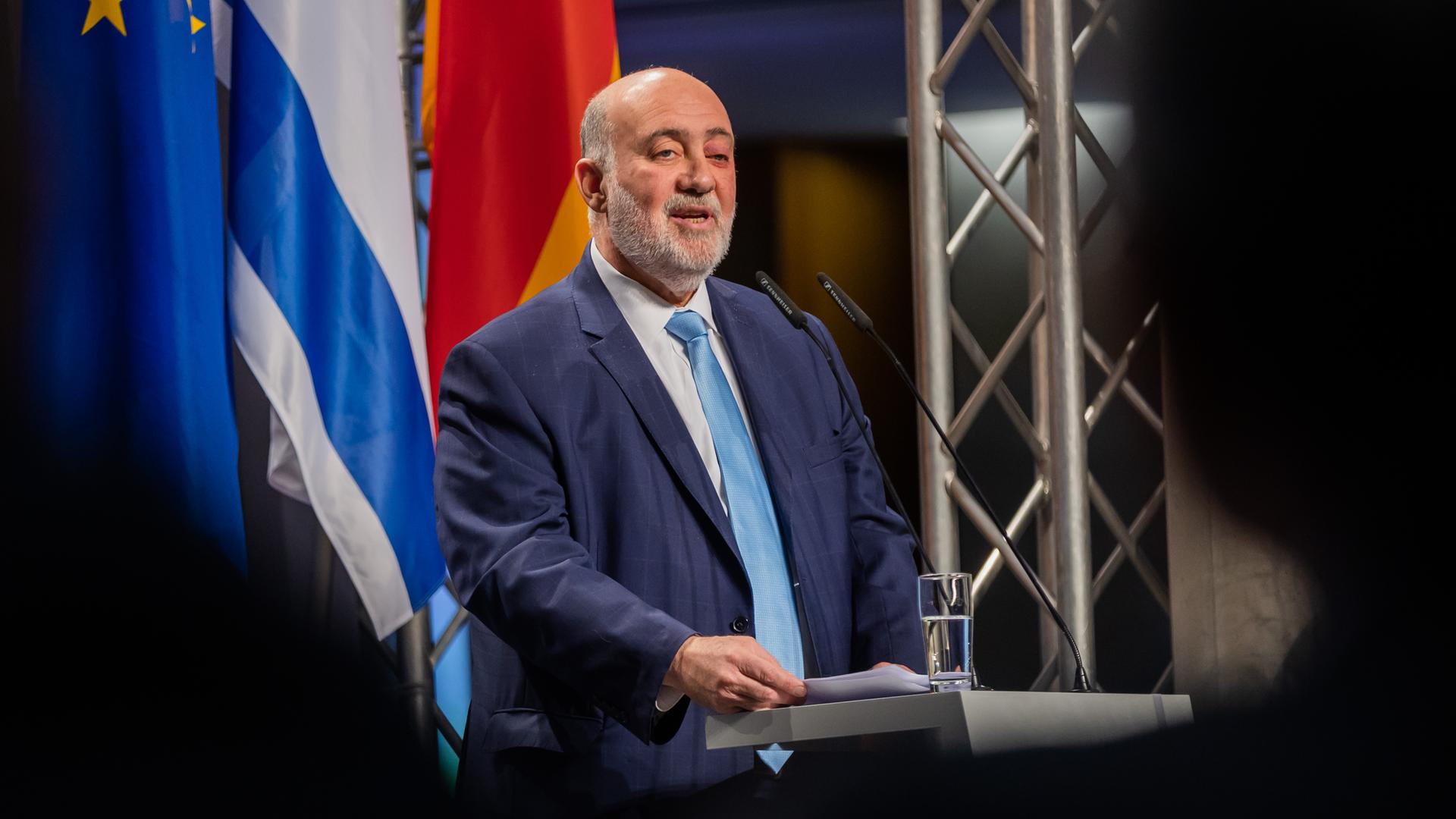 Der israelische Botschafter in Deutschland, Ron Prosor, spricht an einem Rednerpult vor den Flaggen von Israel, Deutschland und der Europäischen Union.
