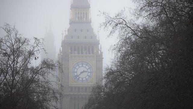 Der Turm des Big Bens in London ist verdeckt von Nebel und umgeben von Ästen verschiedener Bäume. Die Stimmung ist etwas unheimlich.
