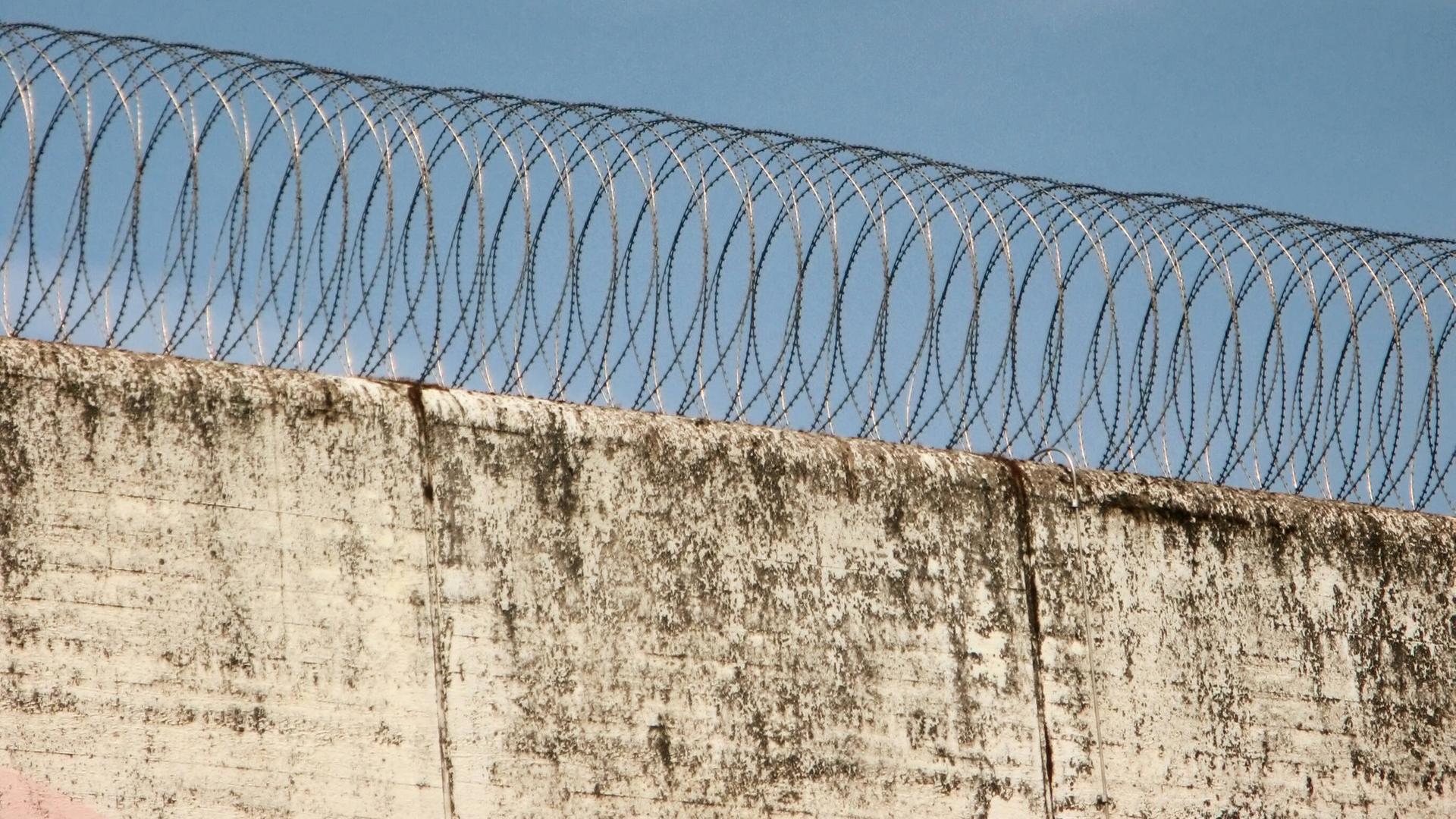 Eine Gefängnismauer mit Stacheldraht. Eine Gefängnismauer mit Stacheldraht.