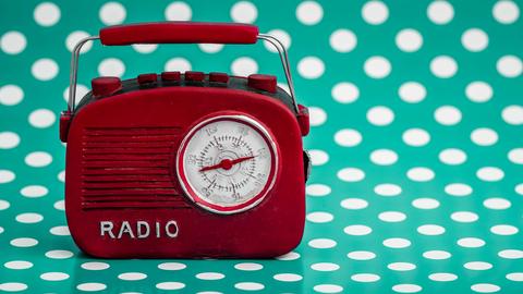 Rotes Retro-Radio vor grünem Hintergrund mit weißen Punkten