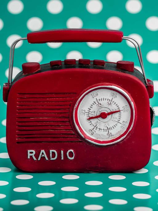 Rotes Retro-Radio vor grünem Hintergrund mit weißen Punkten