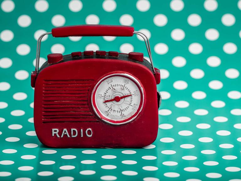 Rotes Retro-Radio vor grünem Hintergrund mit weißen Punkten