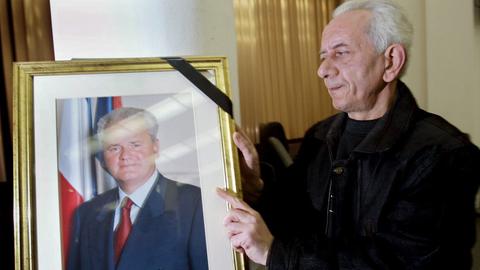 Ein Mitglied der Sozialistischen Partei Serbiens platziert am 11.03.2006 in Belgrad in der Parteizentrale ein Trauerband auf einem Porträtfoto von Serbiens Ex-Präsident Slobodan Milosevic.