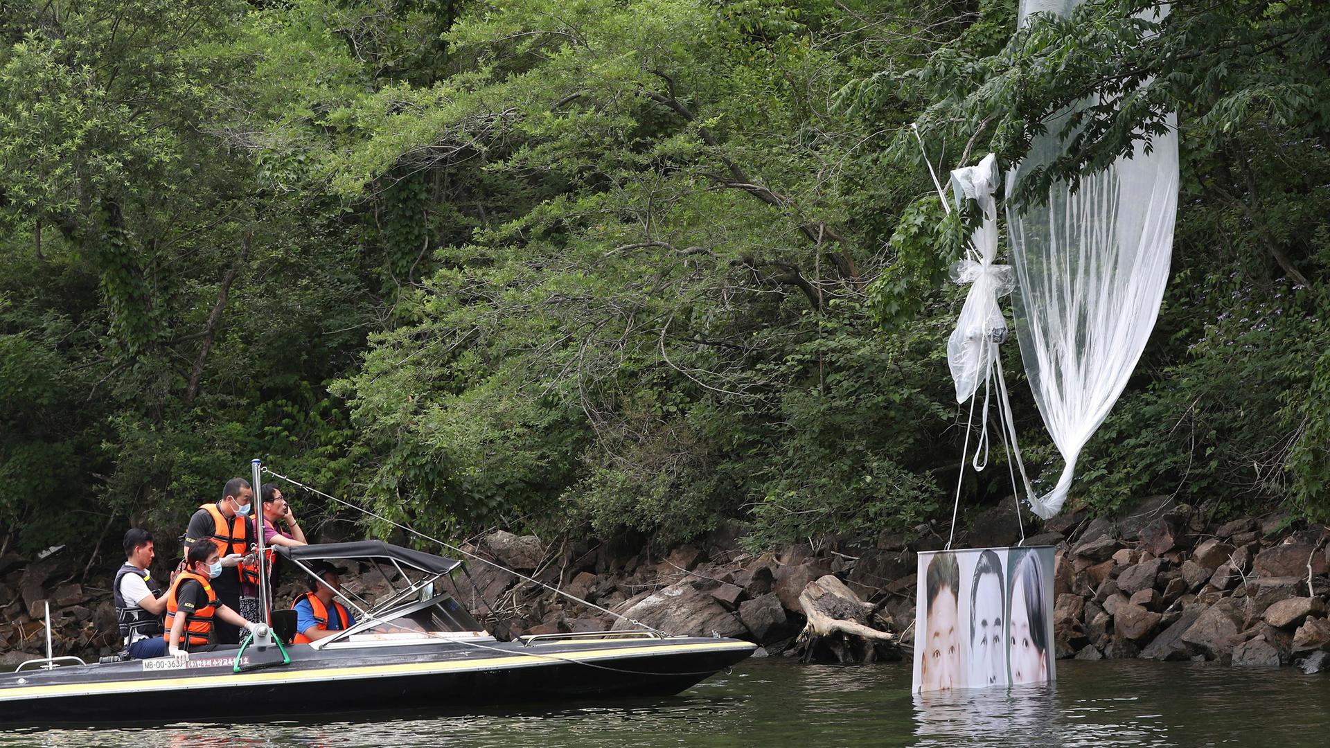ARCHIV - 23.06.2020, Südkorea, Hongcheon: Polizeibeamte fahren mit einem Boot, um einen an einem Baum hängengebliebenen Ballon einzusammeln. ARCHIV - 23.06.2020, Südkorea, Hongcheon: Polizeibeamte fahren mit einem Boot, um einen an einem Baum hängengebliebenen Ballon einzusammeln.