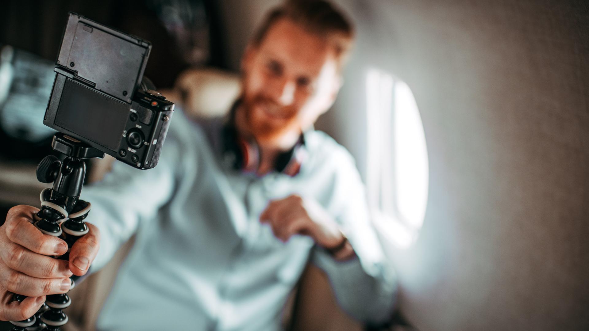 Eine Person mit einer Selfiekamera sitzt in einem Provatflugzeug und filmt sich.