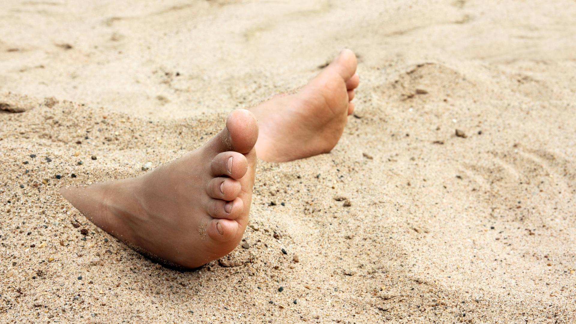 Kinderfüße im Sand am Strand