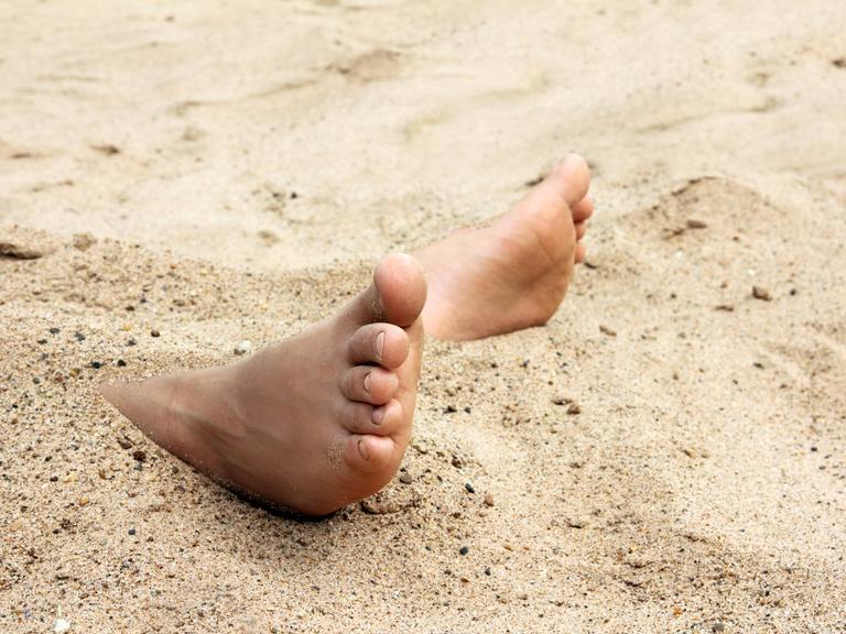 Kinderfüße im Sand am Strand