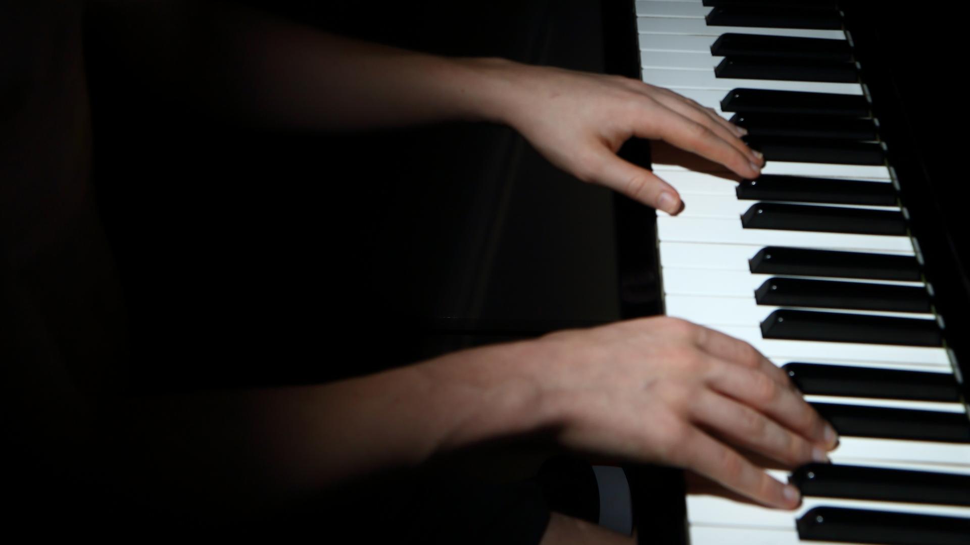 Dunkles Bild von Händen auf einem Klavier. Dunkles Bild von Händen auf einem Klavier.