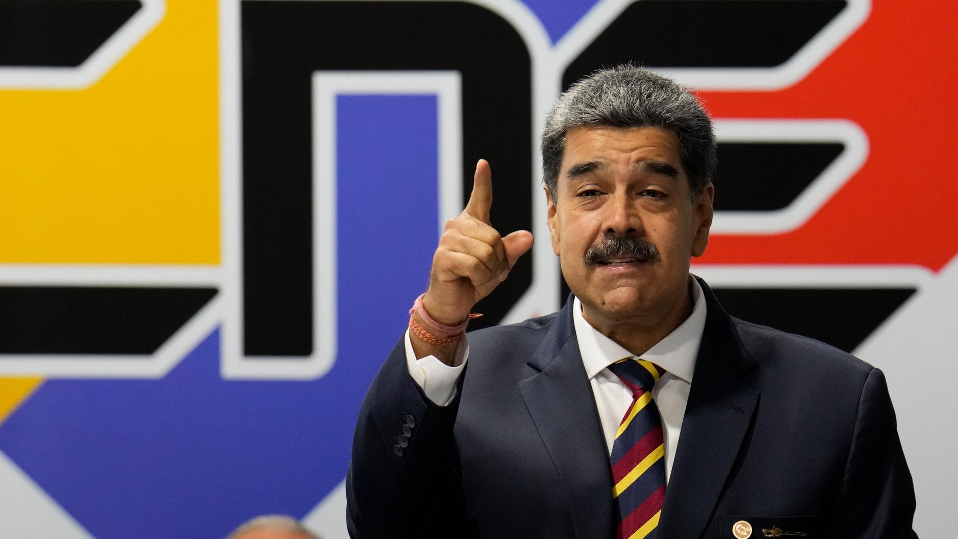 Präsident Nicolas Maduro trägt einen schwarzen Anzug und spricht gestikulierend.