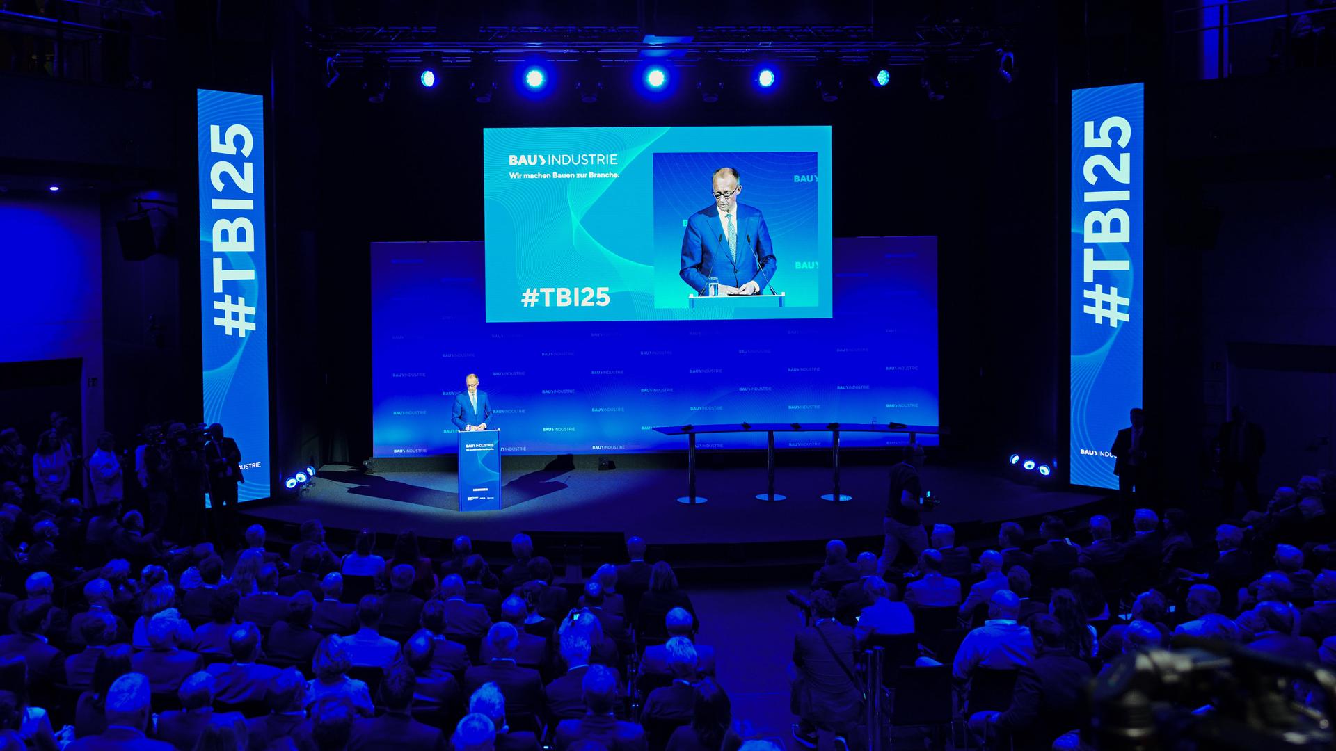 Bundeskanzler Friedrich Merz (CDU) spricht beim Tag der Bauindustrie in Berlin. Er steht im Anzug an einem Rednerpult auf der Bühne; davor sitzen zahlreiche Zuschauer. Die Halle ist in blaues Licht getaucht. Bundeskanzler Friedrich Merz (CDU) spricht beim Tag der Bauindustrie in Berlin. Er steht im Anzug an einem Rednerpult auf der Bühne; davor sitzen zahlreiche Zuschauer. Die Halle ist in blaues Licht getaucht.