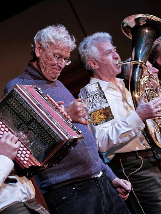 Gerhard Polt und die Well-Brüder musizierend auf der Bühne. Gerhard Polt und die Well-Brüder musizierend auf der Bühne.