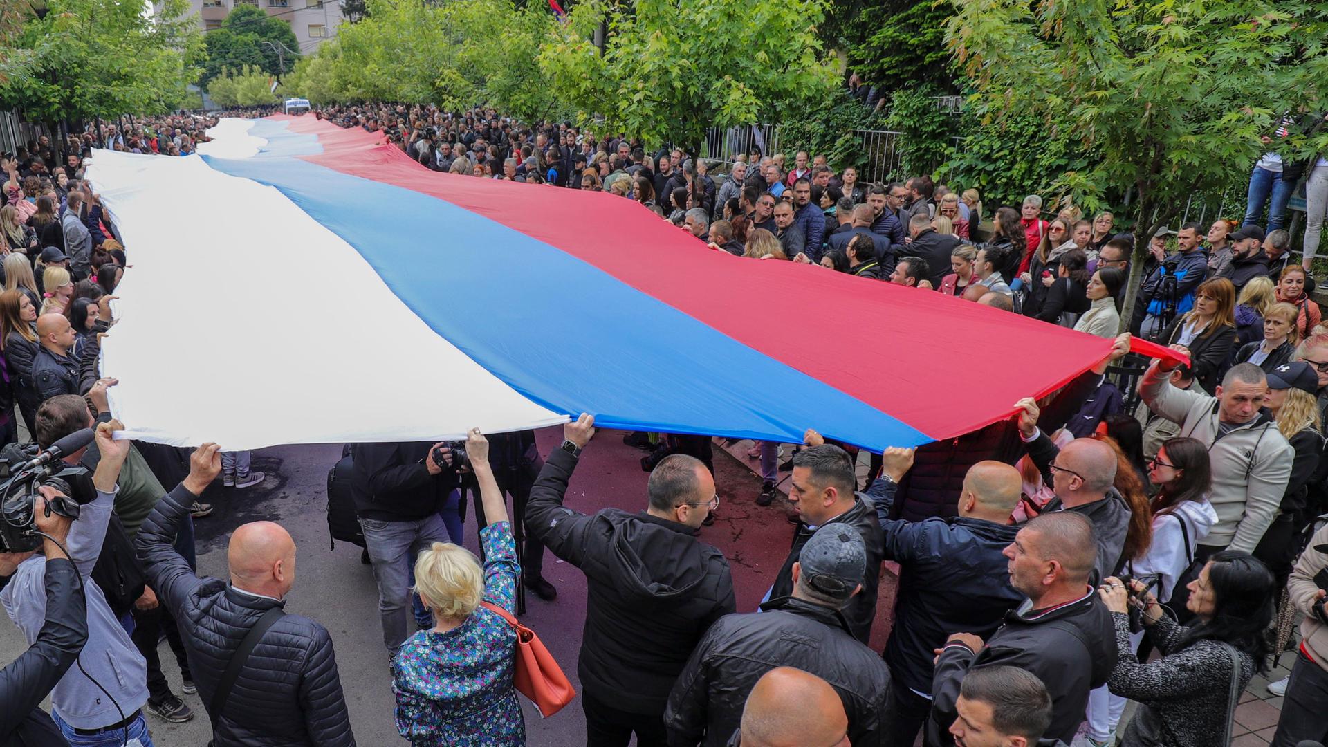 Menschen halten eine riesige serbische Flagge während ihres Protestes in Zvecan im Kosovo hoch. Menschen halten eine riesige serbische Flagge während ihres Protestes in Zvecan im Kosovo hoch.