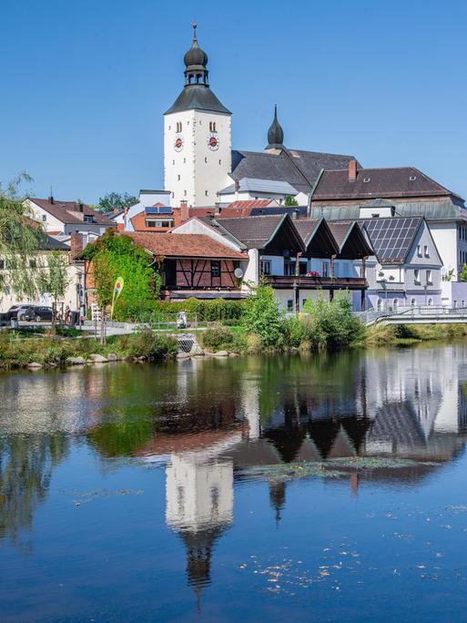 In einem Gewässer spiegelt sich die Silhouette einer bayerischen Stadt