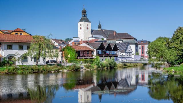 In einem Gewässer spiegelt sich die Silhouette einer bayerischen Stadt