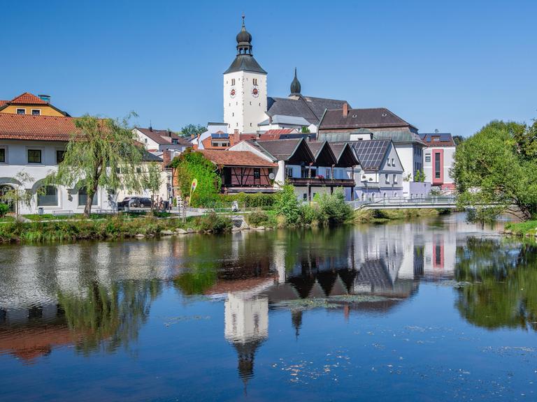 In einem Gewässer spiegelt sich die Silhouette einer bayerischen Stadt