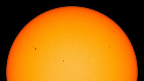 Eine Teleskop-Total-Aufnahme der Sonne zeigt verschiedene unregelmäßig verteilte, dunkle Flecken