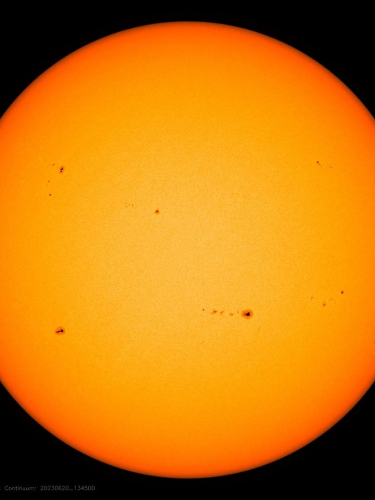 Eine Teleskop-Total-Aufnahme der Sonne zeigt verschiedene unregelmäßig verteilte, dunkle Flecken